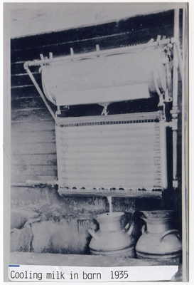 1935 – Milk Cooling, Raw milk from the cows was cooled on this device. The top tank had clothespins holding flannel. The milk was poured in through the flannel and it was drawn out through a spigot that could regulate the low of milk as it went into the top tray. The tray had small holes. As the milk flowed out, it spread over tubes with cold brine running through them. Milk cans caught the cooled milk, which were then brought to the milk plant for pasteurization and bottling.