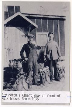 1935 – Ray Moran and Albert Shaw in front of the milk house with milking cans.