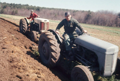 Tractor working – Two Ferguson tractors plowing corn field on Shaw farm by Warren Shaw Sr. and Bob Gagnon. Spring 1960