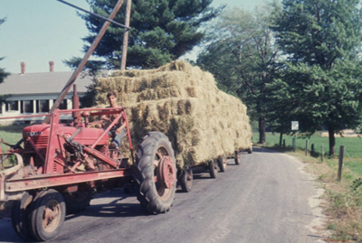 1960 – Large double load of hay going by the Shaw Farm on the way to the Steve Neofotistos farm nearby.